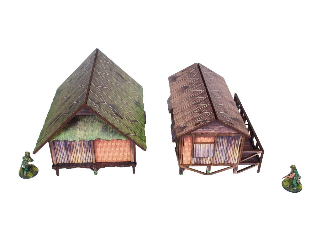 WW2 Pacific Jungle Huts (2) PREPAINTED – dwie zmontowane chaty dżunglowe na palach, widok z przodu pod kątem: zielona strzecha (lewa) i brązowa strzecha z werandą (prawa), figurki żołnierzy 28mm Bolt Action, białe tło
