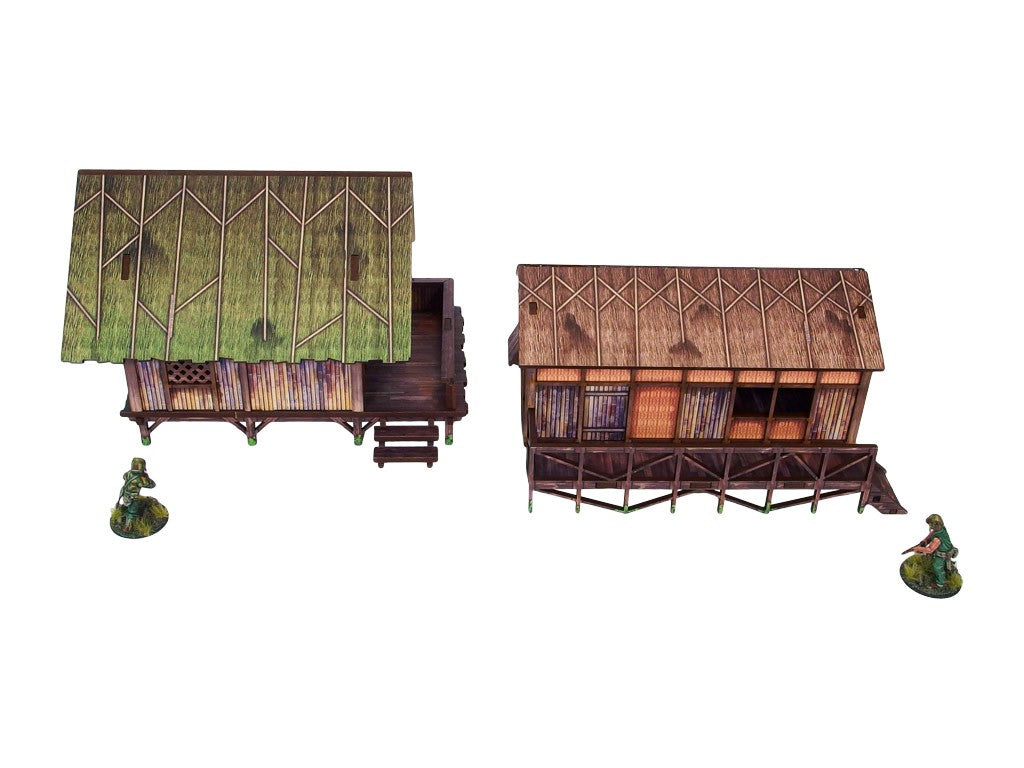 WW2 Pacific Jungle Huts (2) PREPAINTED – dwie zmontowane chaty dżunglowe na palach, widok z przodu: zielona strzecha (lewa) i brązowa strzecha (prawa) z werandą i schodami, figurki żołnierzy 28mm Bolt Action, białe tło
