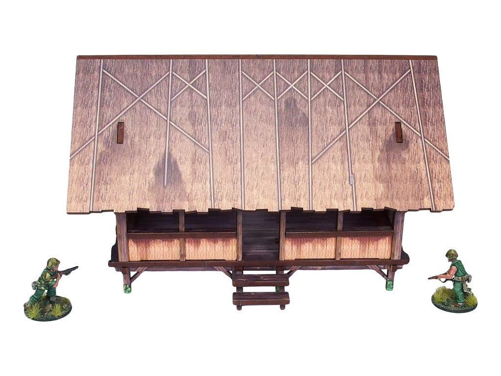 WW2 Pacific Kitchen (1) PREPAINTED – zmontowana kuchnia dżunglowa na palach, widok z przodu: otwarty budynek z dachem ze strzechy w rombowy wzór i bambusowymi ścianami, dwie figurki żołnierzy 28mm Bolt Action, białe tło
