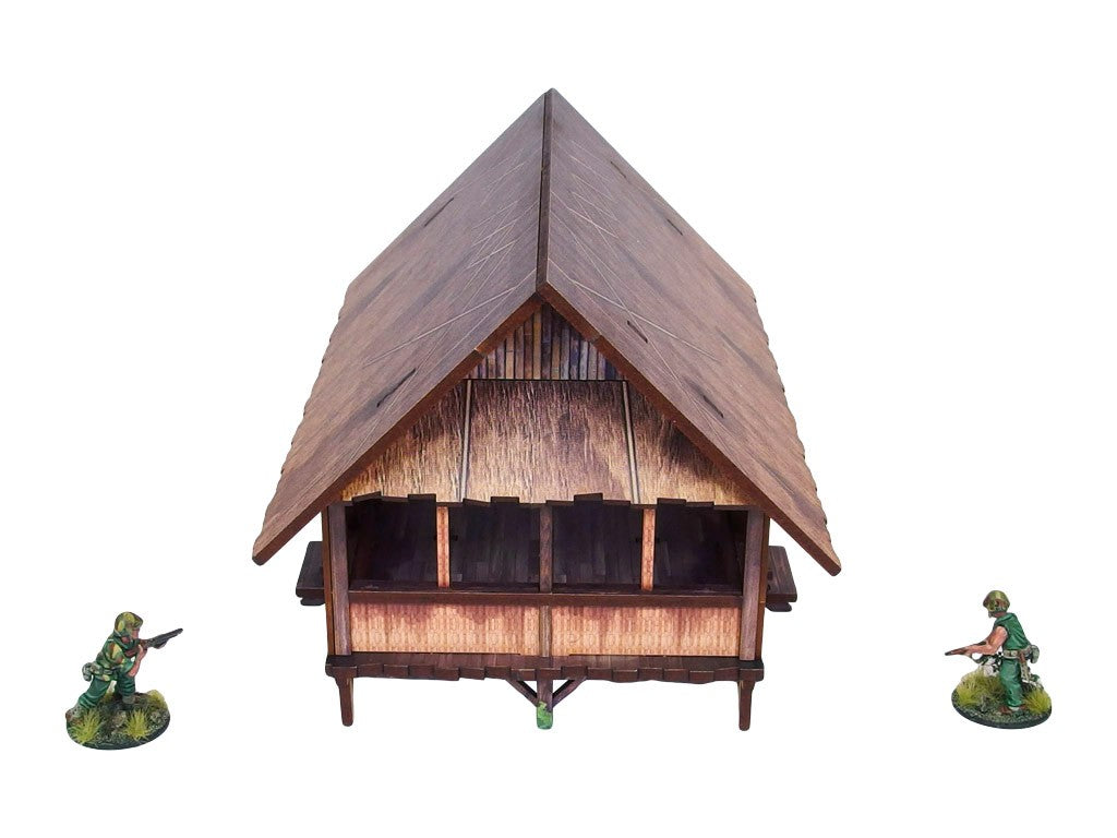 WW2 Pacific Kitchen (1) PREPAINTED – zmontowana kuchnia dżunglowa na palach, widok z boku: spiczasty dach ze strzechy z bambusowymi ścianami i otwartą przestrzenią wewnętrzną, dwie figurki żołnierzy 28mm Bolt Action, białe tło
