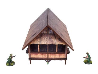 WW2 Pacific Kitchen (1) PREPAINTED – zmontowana kuchnia dżunglowa na palach, widok z boku: spiczasty dach ze strzechy z bambusowymi ścianami i otwartą przestrzenią wewnętrzną, dwie figurki żołnierzy 28mm Bolt Action, białe tło
