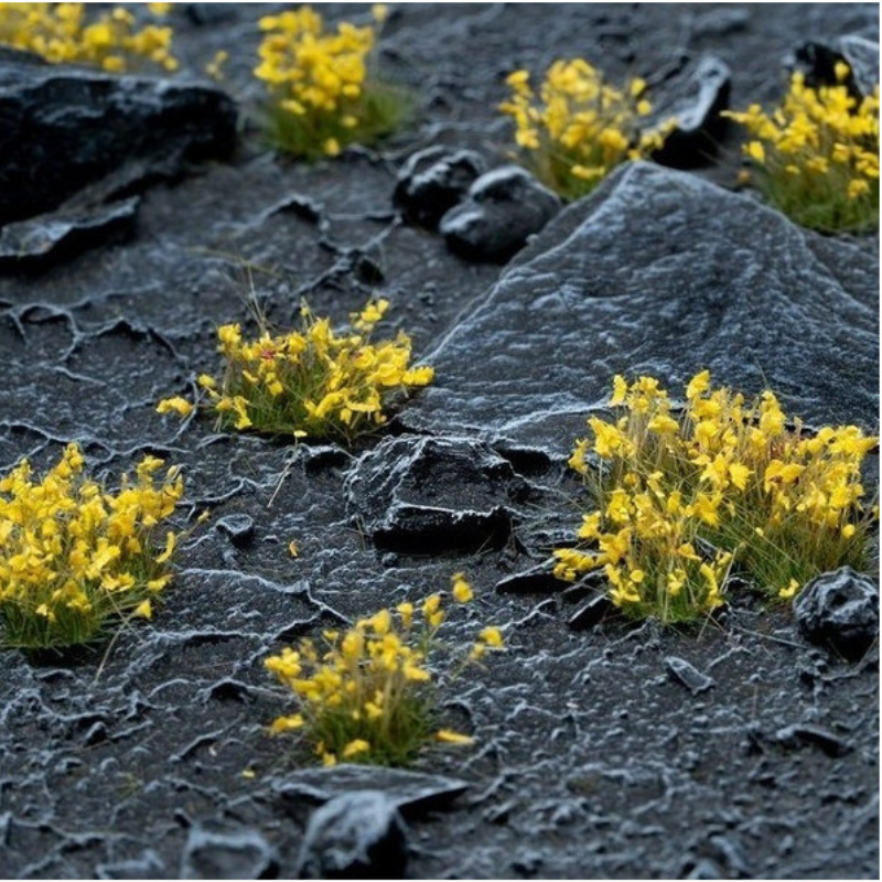 Yellow Flowers 6mm Wild Gamers Grass - diorama z czarnymi skałami i ciemną ziemią pokryta żółtymi kępkami kwiatowymi tworzącymi intensywny kontrast kolorystyczny
